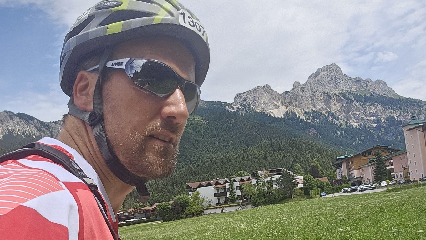 E-Bike Touren rund um Oberjoch Mann mit Fahrradhelm und Sonnenbrille vor Berglandschaft und Wiesen