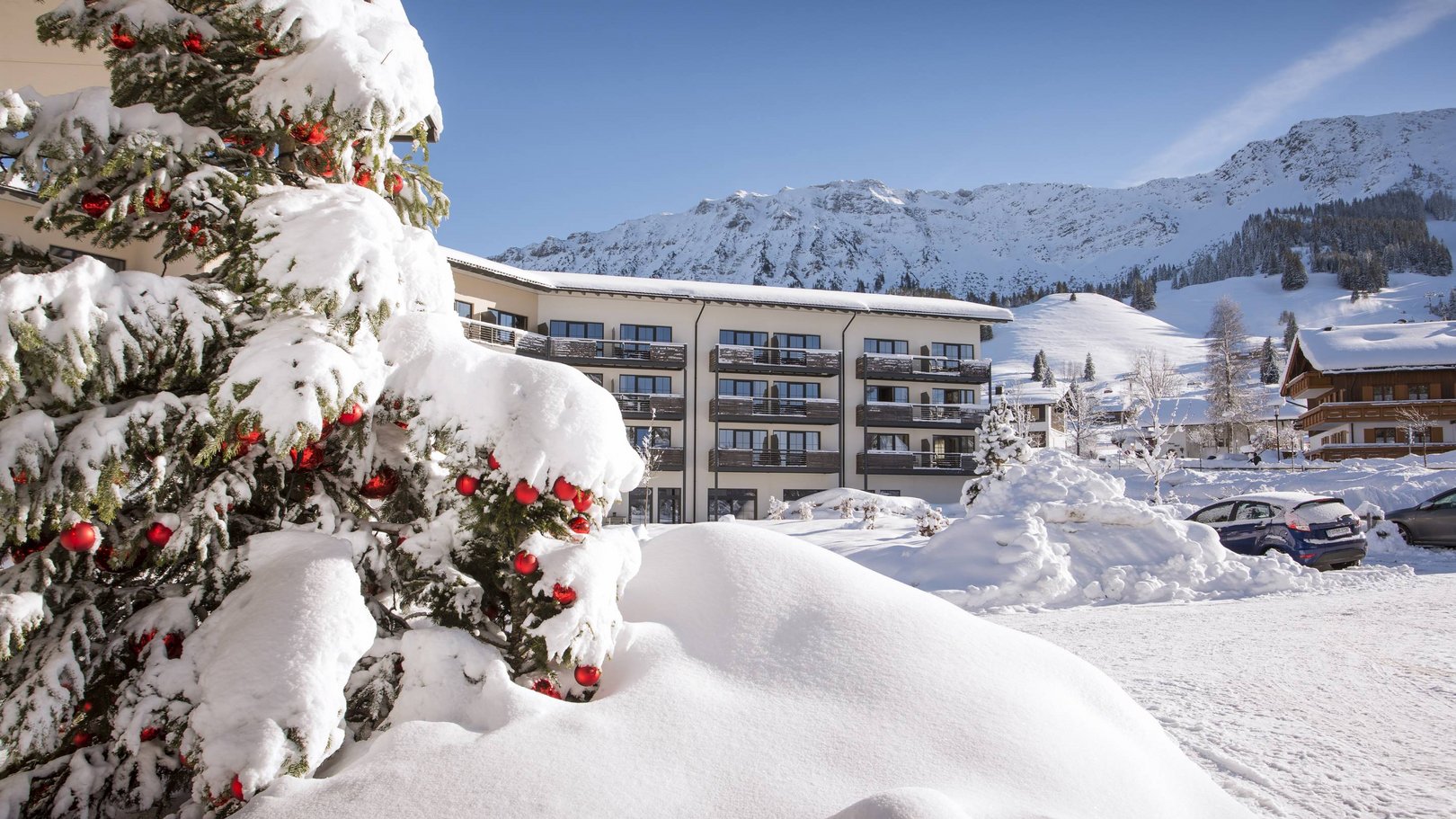 Veranstaltungen im Panoramahotel Oberjoch Schneebedeckter Weihnachtsbaum vor Hotel mit Bergen im Hintergrund