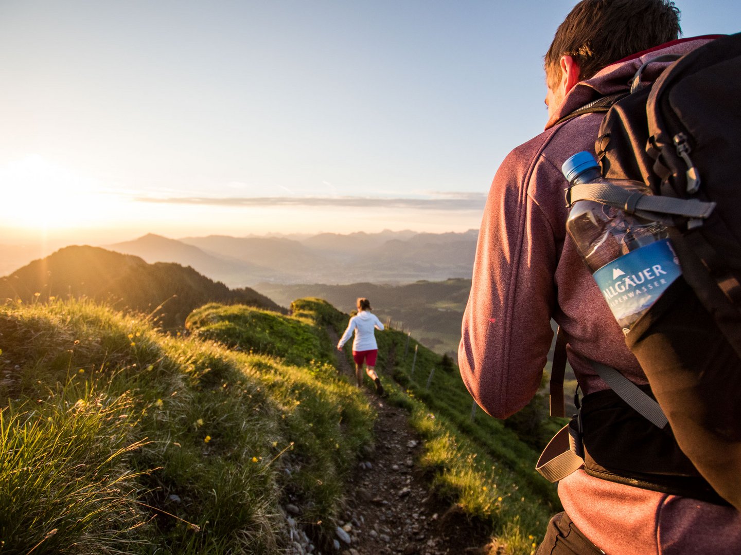 Panoramahotel Oberjoch | Unsere Lieferanten Wanderer mit Rucksack auf einem Bergpfad bei Sonnenuntergang