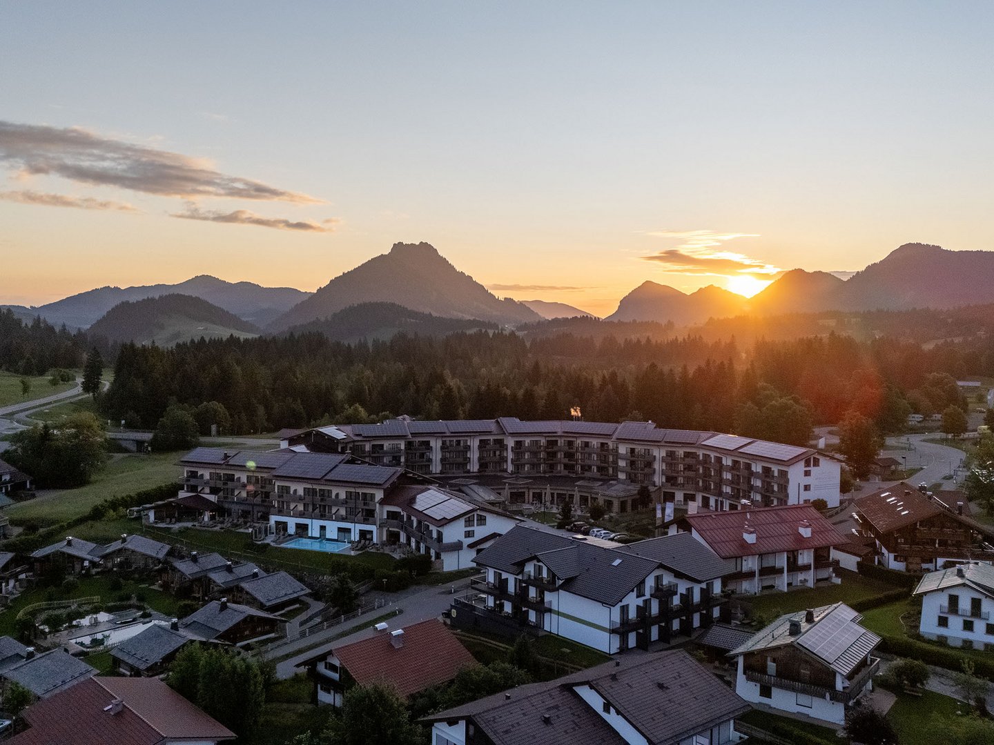 Autofrei in Das Weitblick Allgäu reisen Dorf mit Häusern und Bergen bei Sonnenuntergang