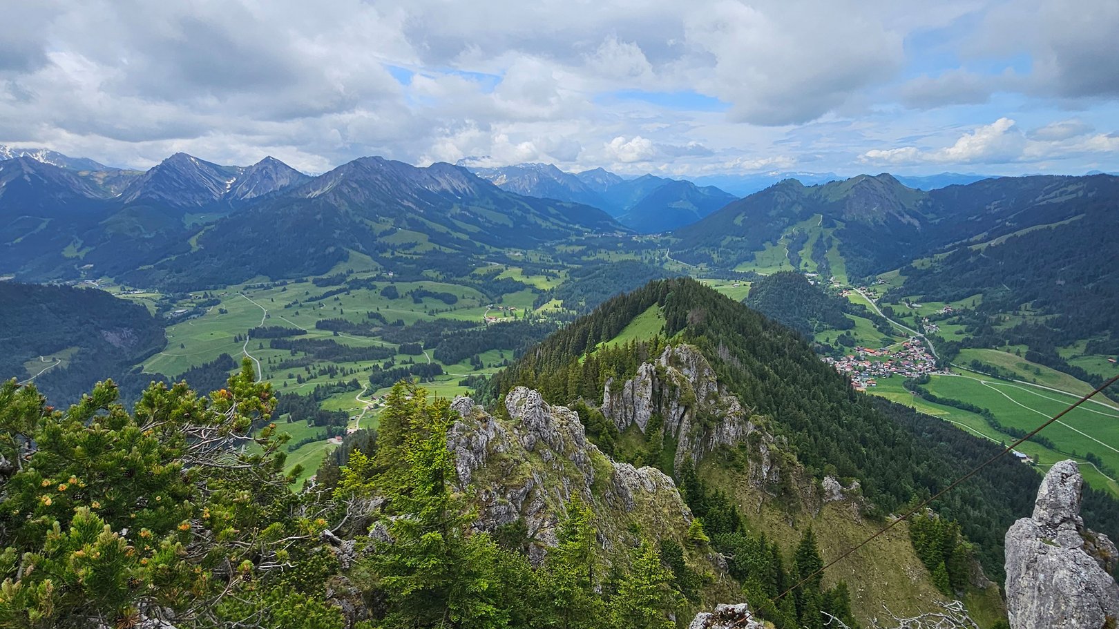 Exklusive Wandertipps von Basti Bergblick mit Felsen, grünen Wäldern und Tal unter bewölktem Himmel