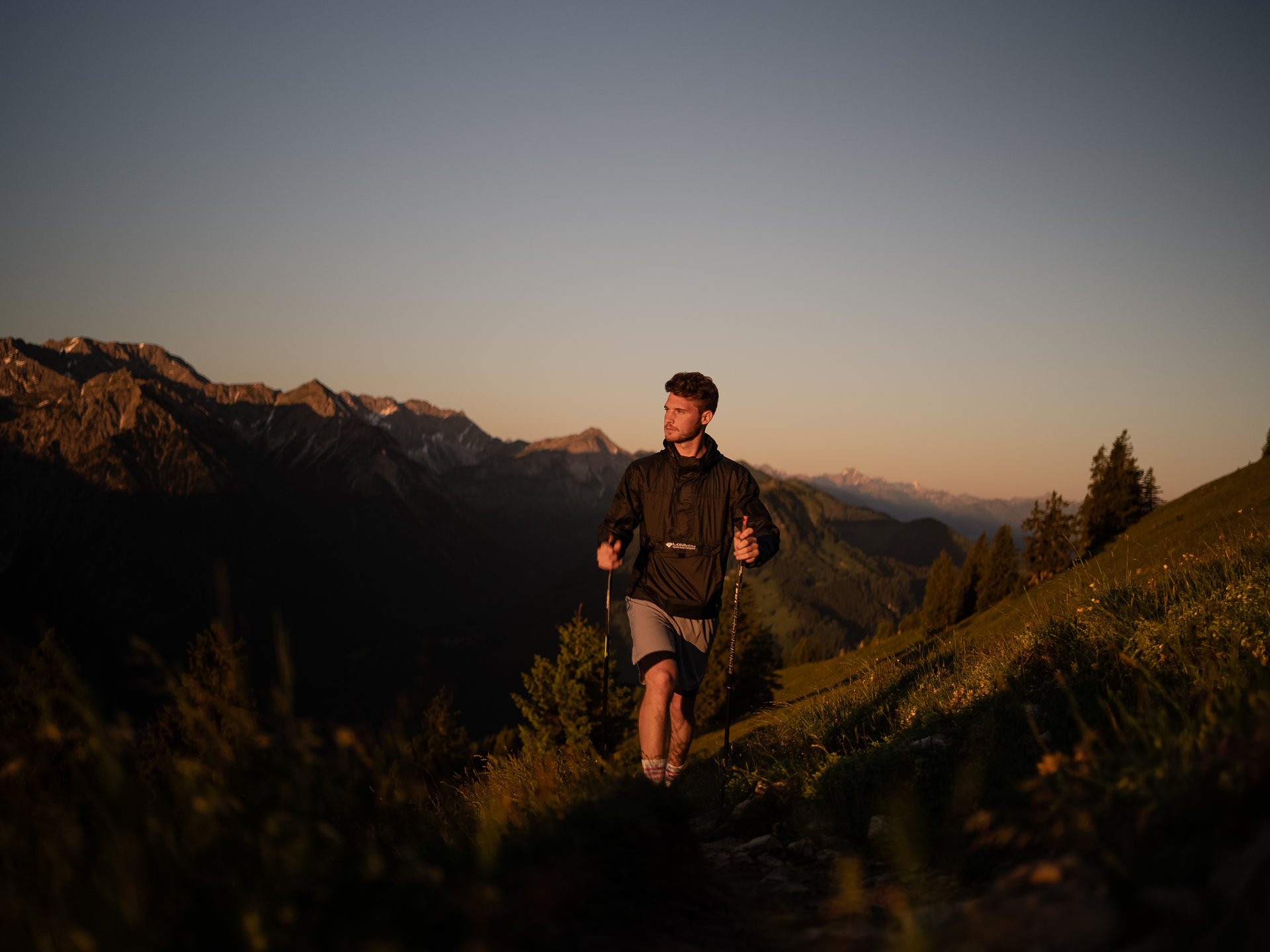Entspannte Tage im 4*S Panoramahotel Oberjoch! Mann wandert mit Stöcken auf Bergpfad bei Sonnenuntergang