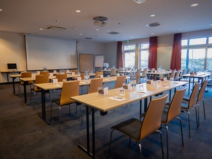 Inklusivleistungen & mehr | Panoramahotel Oberjoch Konferenzraum mit Tischen, Stühlen, Wasserflaschen und Projektor