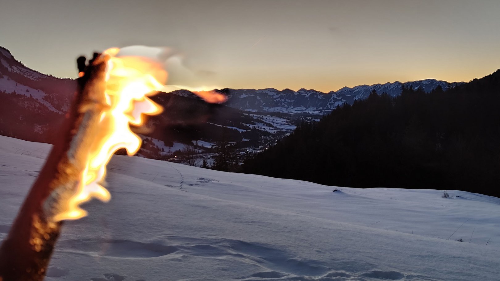 Seminarverpflegung | Panoramahotel Oberjoch Brennende Fackel vor verschneiter Berglandschaft bei Sonnenuntergang