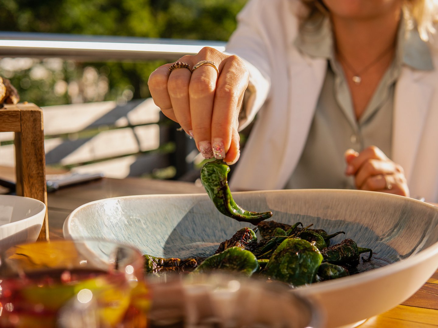 Zwölfhundert NN | Restaurant | Panoramahotel Oberjoch Hand nimmt geröstete grüne Paprika aus einer Schüssel auf einem Holztisch