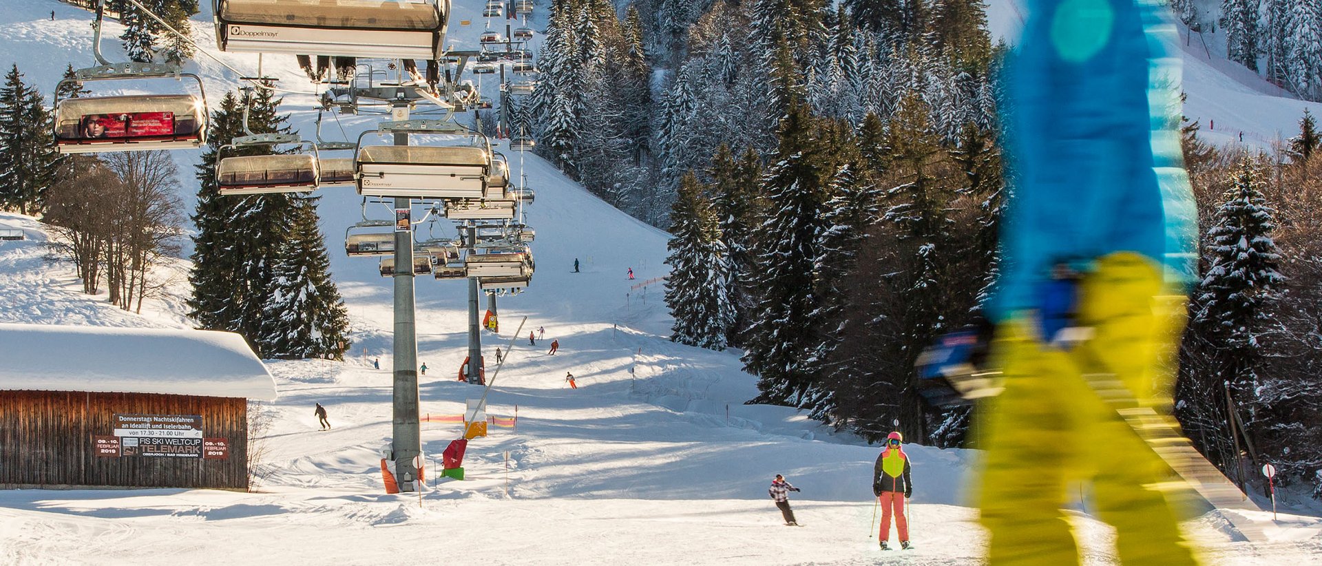Skifahren lernen im Herzen des Allgäus Skifahrer auf Piste mit Sessellift und verschneiten Bäumen im Hintergrund